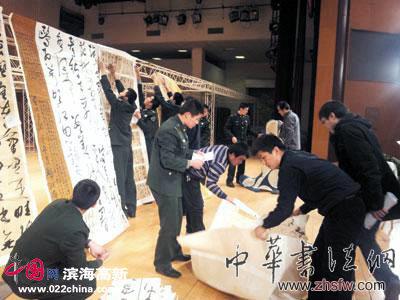 工作人員和武警戰(zhàn)士懸掛評審作品