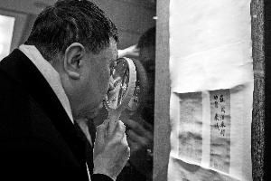 收藏家劉文杰用高倍放大鏡觀看《功甫帖》。