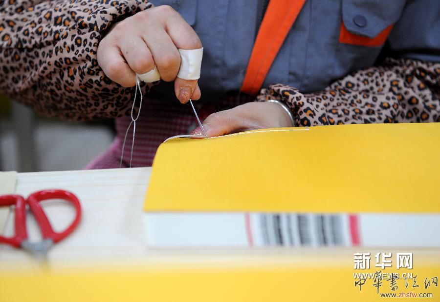 4月17日，裝訂車間工人在為裝訂中的《四庫全書》書冊穿線。