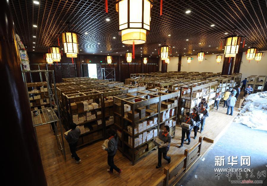 4月16日，在揚州天寧寺萬佛樓的《四庫全書》首套復制件布展工作現(xiàn)場，工作人員將書冊搬運到楠木書架上。