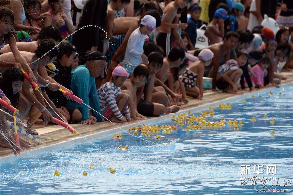 （5）2013年7月14日，在日本東京，人們往游泳池中放置縮小版的“大黃鴨”。 新華社/法新（張帆編輯）